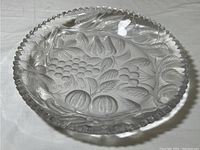 Top-down image showing the entire cut glass dish with fruit design and scalloped edges.