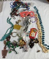 Full lot of assorted costume jewelry including necklaces, bracelets, and pendants spread out on white background.