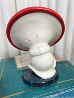 Ceramic mushroom figurine from Disney's Fantasia showing the back side with red cap, white body and a dark blue base.