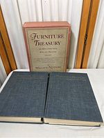 Two hardcover books and slipcase displayed on table; slipcase behind books showing title and author