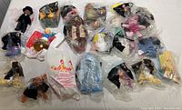 Overhead photo of multiple McDonald's Happy Meal toys, some sealed in original plastic bags, arranged on a white surface.