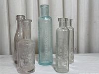 Five small medicine bottles arranged on white surface, showing overall shape and color variation.