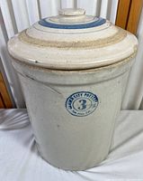 Front view of the crock showing Garden City Pottery blue stamp and lid on top.