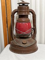 Front view of vintage PG&E metal lantern with red glass globe showing condition and metal frame.
