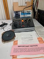 Overview of the Sound & Power 7000 control unit with illuminated power indicators, including the original instruction sheets and power cable on a white surface.