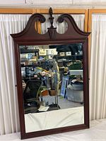 Front view of the wood framed mirror showing full reflective surface and ornate top.