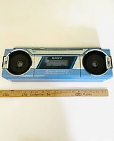 Front view showing dual speakers, cassette window, Sony and Auto Reverse branding in blue housing.