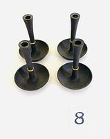 Four matte black cast iron candle holders arranged in a square