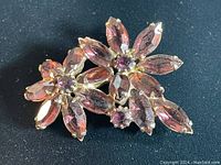 Front view of the vintage gold-tone flower brooch with purple marquise and round prong-set stones.