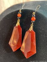 Front and side views of the two drop style earrings with large faceted carnelian stones and smaller round beads above, gold-tone metal caps and hooks