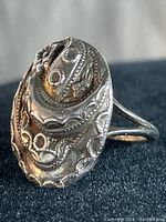 Top view of vintage ornate sterling silver ring showing detailed engraved floral and geometric patterns on oval face.