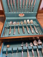 Flatware in original blue case showing various forks, spoons, knives neatly arranged with the 1847 Rogers label.