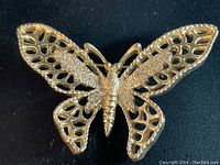 Front view of vintage Sara Coventry signed gold tone butterfly brooch showing detailed openwork wings and segmented body