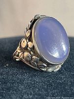 Close-up angle showing the large oval purple cabochon stone and detailed floral design on the sterling silver band of the vintage ring.