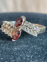 Close-up front view of vintage sterling silver ring showing two marquise burgundy stones and multiple clear stones set in bands.