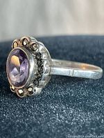 Side angle view showing sterling silver band and faceted oval amethyst stone with marcasite accents around the bezel setting.