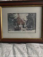 Framed artwork depicting a winter house scene with snow-covered trees and bushes.