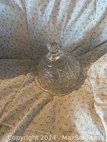Clear crystal butter dish with a lid, displayed on a fabric background showing its intricate faceted pattern and knob handle on top.