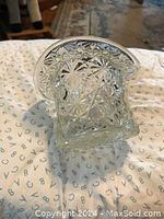 Top hat shaped crystal pen holder with intricate cut patterns shown on a fabric surface