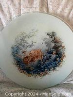 Close-up of the painted scene on one of the plates showing figures, flowers, and delicate color details