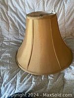 Image of copper-colored silk lamp shade with a flared shape and vertical panel stitching showing general condition and dimensions.