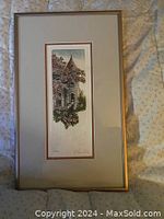 Full view of original signed and framed artwork showing gold frame and white matte with brown inner border. Artwork depicts a stone building surrounded by flowers.