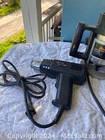 Photo showing black plastic heat gun with power cord.