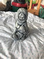 Front view of small soapstone carving showing a child in an Inuit parka holding a bear cub on lap