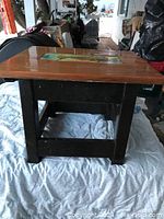 Overall view of the sturdy wooden stool showing natural wood top and black painted legs.