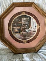 Front view of framed collector plate depicting a cozy Christmas scene with fireplace and armchair