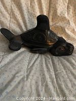 Black carved orca/whale sculpture with traditional West Coast indigenous motifs on a light background fabric.