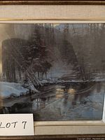 Framed print showing a river flowing through a snow-covered forest area in winter with trees on both sides.