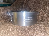 Photo showing the stainless steel pan with side handles and caution text embossed on the side.
