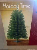 Photo of the artificial 3.5 foot Canadian pine Christmas tree with green plastic stand, unadorned, in its packaging box showing the tree image and brand Holiday Time.