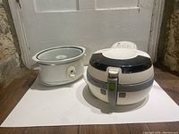 Both items shown side by side: T-Fal ActiFry air fryer and white crockpot on flat white surface.