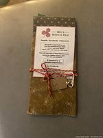 Three folded beeswax wraps stacked with visible colors and patterns alongside a printed instruction card, tied with red and white twine.