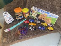 Overview of various children's activity items including animal figurines, modeling clay, magnetic alphabet, bead necklaces, toy vehicles and puzzle kits.