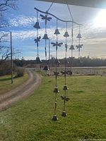 Wind chime hanging outdoors under a porch roof with visible dragonfly metal shapes and multiple small hanging bells.