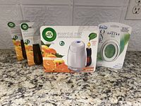 Photo of Air Wick Essential Mist diffuser, three refill bottles, and Febreze Small Spaces bamboo air freshener on countertop.