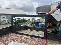 Photo of the floor length beveled mirror with painted black frame standing on a truck bed with outdoor background.