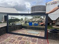 Large black framed beveled mirror placed in the back of a truck bed, showcasing full mirror and frame dimensions.