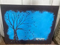Full view of the original mixed media artwork titled 'HOPE' showing a black tree on a blue background with black border and 'HOPE' text.