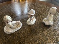 Three Enesco Precious Moments figurines displayed on ornate table showing overall size and detail.