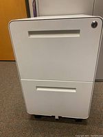 Front view of white filing cabinet showing two drawers and lock on top drawer.