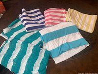 Five pieces of folded striped knit fabrics in various colors on a table.