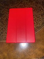 Closed red tablet cover with tri-fold flap, rectangular shape