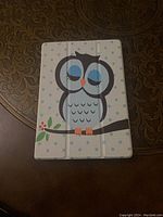 Front of tablet cover showing owl illustration with light blue polka dots on white background.