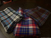 Three folded winter weight plaid fabric pieces shown on a table.