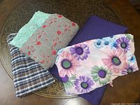 Five pieces of summer fabric in different colors and patterns, displayed together on a round metallic tray.