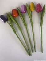 Set of six wooden tulip flowers arranged side by side, showing different colors and green stems.